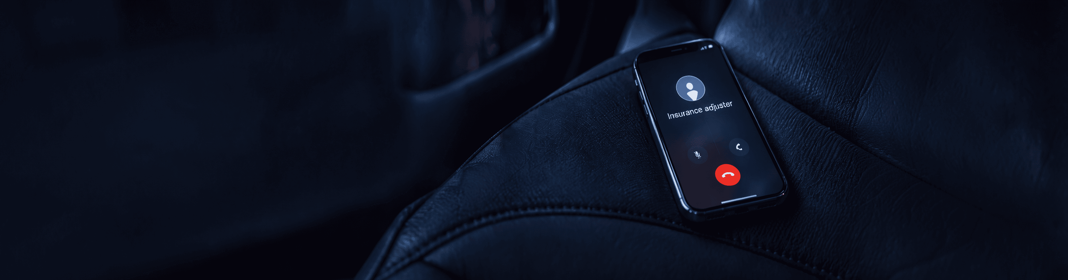 Un teléfono sobre el asiento de un auto de noche, con una llamada entrante de un ajustador de seguros