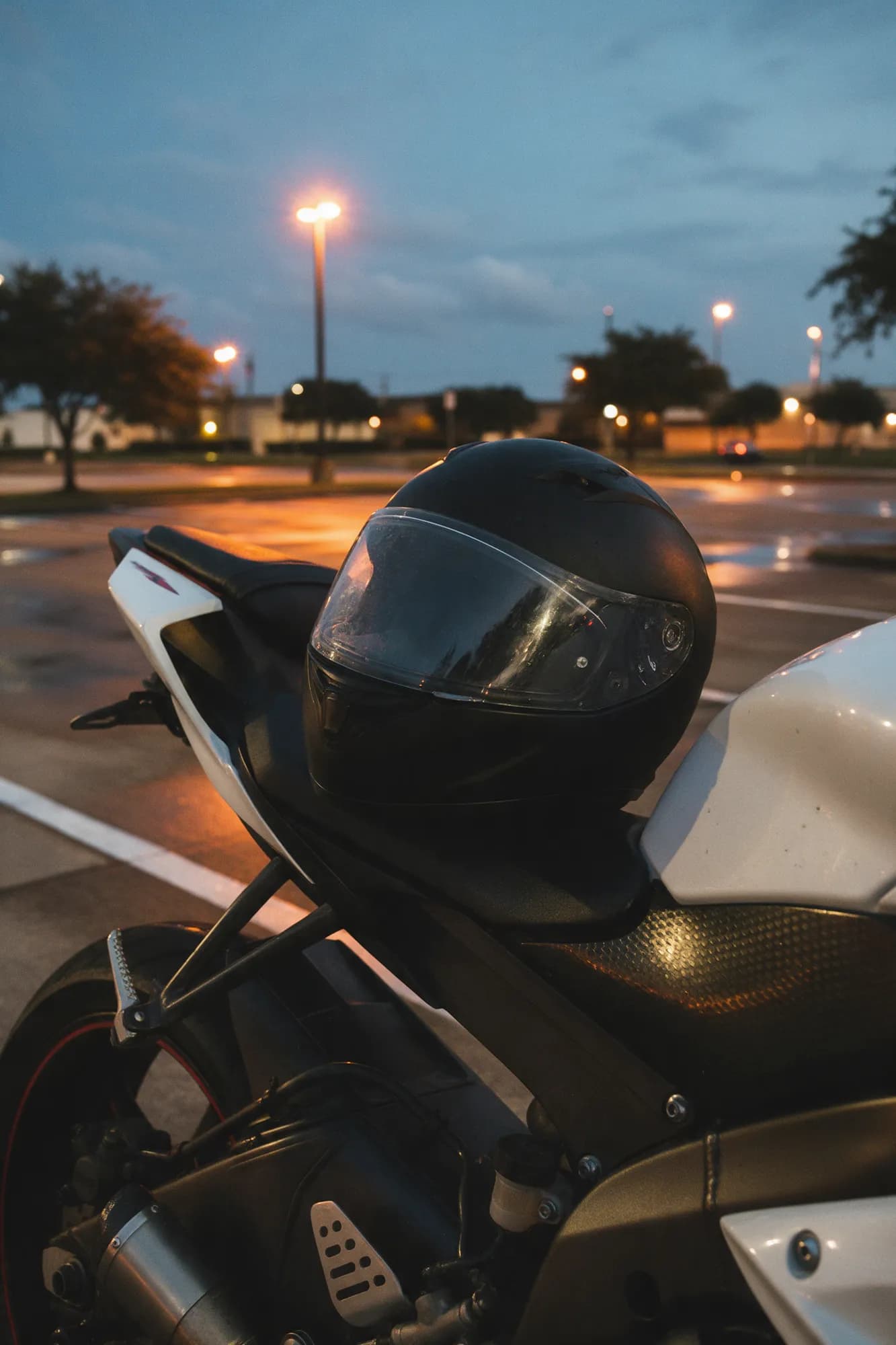 A black full-face helmet resting on a parked motorcycle at dusk